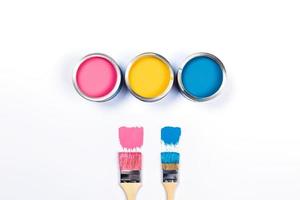 bianca sfondo con tre colorato dipingere barattoli e spazzole. foto