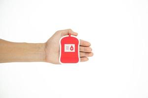 mani Tenere sangue imballare carta tagliare su bianca sfondo, sangue trasfusione, mondo sangue donatore giorno. sangue donazione e Salvataggio vita concetto foto