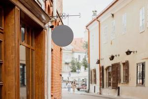 vuoto cartello finto su, su il facciata nel vecchio cittadina. copia spazio per il tuo memorizzare cartello o logo. moderno vuoto all'aperto segnaletica, modello per Inserisci azienda logo. grigio il giro memorizzare cartello. foto