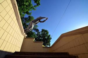 un' giovane tipo esegue un' saltare attraverso il spazio fra il calcestruzzo parapetti. il atleta pratiche parkour, formazione nel strada condizioni. parte inferiore Visualizza foto