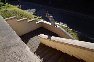 un' giovane tipo esegue un' saltare attraverso il spazio fra il calcestruzzo parapetti. il atleta pratiche parkour, formazione nel strada condizioni. il concetto di gli sport sottoculture tra gioventù foto