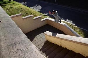 un' giovane tipo esegue un' saltare attraverso il spazio fra il calcestruzzo parapetti. il atleta pratiche parkour, formazione nel strada condizioni. il concetto di gli sport sottoculture tra gioventù foto