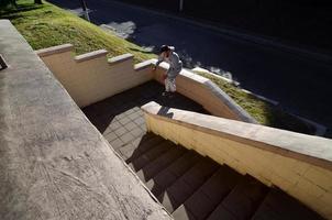 un' giovane tipo esegue un' saltare attraverso il spazio fra il calcestruzzo parapetti. il atleta pratiche parkour, formazione nel strada condizioni. il concetto di gli sport sottoculture tra gioventù foto