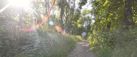 un' giovane tipo nel un' grigio gli sport completo da uomo corre lungo il sentiero tra il foto