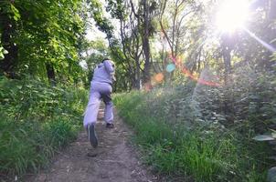 un' giovane tipo nel un' grigio gli sport completo da uomo corre lungo il sentiero tra il foto