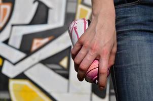 foto di un' ragazze mano con aerosol dipingere lattine nel mani su un' graffiti parete sfondo. il concetto di strada arte e uso di aerosol vernici. graffiti arte negozio sfondo Immagine