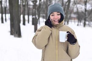 inverno ritratto di giovane ragazza con smartphone e caffè tazza foto