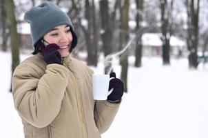 inverno ritratto di giovane ragazza con smartphone e caffè tazza foto