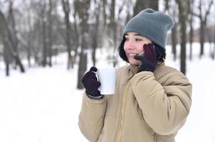 inverno ritratto di giovane ragazza con smartphone e caffè tazza foto