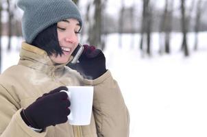 inverno ritratto di giovane ragazza con smartphone e caffè tazza foto