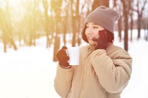 inverno ritratto di giovane ragazza con smartphone e caffè tazza foto