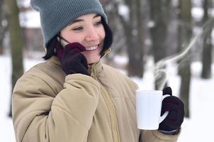 inverno ritratto di giovane ragazza con smartphone e caffè tazza foto