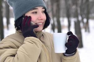 inverno ritratto di giovane ragazza con smartphone e caffè tazza foto