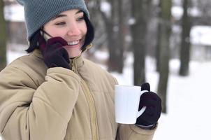 inverno ritratto di giovane ragazza con smartphone e caffè tazza foto