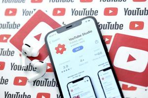 Kharkov, Ucraina - marzo 5, 2021 Youtube studio icona e applicazione a partire dal App memorizzare su i phone 12 professionista Schermo schermo con airpods professionista su bianca tavolo foto