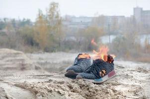 ardente gli sport scarpe da ginnastica o Palestra scarpe su fuoco In piedi su sabbioso spiaggia costa. atleta bruciato fuori. fisico sforzo durante formazione concetto foto