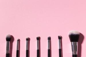 vario trucco spazzole su rosa sfondo con copia spazio, superiore Visualizza. cosmetici e bellezza concetto. foto