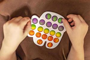 pop esso è un' multicolore anti stress giocattolo nel figli di mani. bolla gioco. anti stress giocattoli. foto