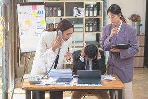 un' squadra di tre asiatico uomini d'affari è Lavorando dentro un ufficio dove uomini d'affari nel nero tute siamo essere ordinato di loro supervisori e boss un' lotto causando fatica a opera. bruciato concetto foto