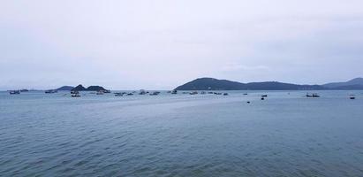 molti coda lunga barca e velocità barca su mare. veicolo su oceano con bianca cielo e montagna sfondo con copia spazio su superiore o sopra. paesaggio di Visualizza a Phuket, Tailandia. viaggio e viaggio. paesaggio marino foto