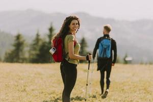 coppia sorridente che cammina con zaini su verdi colline foto