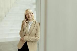 donna d'affari utilizzando mobile Telefono su moderno ufficio corridoio foto