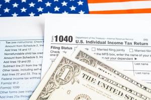modulo di dichiarazione dei redditi 1040 con bandiera usa america e banconota in dollari, reddito individuale statunitense. foto