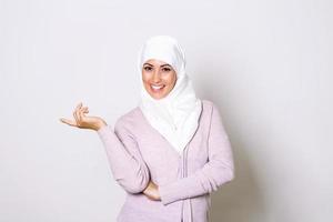 moderno, elegante e contento musulmano donna indossare un' foulard. arabo Arabia Emirates donna coperto con beige sciarpa. uno donne Sorridi con bianca sfondo foto