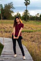 asiatico donna in piedi su di legno ponte su riso campo durante tramonto tempo foto