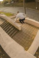 un' giovane tipo esegue un' saltare attraverso il spazio fra il calcestruzzo parapetti. il atleta pratiche parkour, formazione nel strada condizioni. il concetto di gli sport sottoculture tra gioventù foto