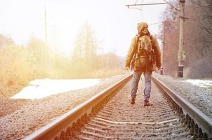 un' uomo con un' grande zaino va avanti su il ferrovia traccia duri foto