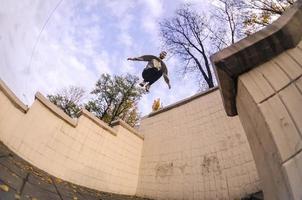 un' giovane tipo esegue un' saltare attraverso il spazio fra il calcestruzzo parapetti. il atleta pratiche parkour, formazione nel strada condizioni. il concetto di gli sport sottoculture tra gioventù foto