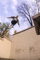 un' giovane tipo esegue un' saltare attraverso il spazio fra il calcestruzzo parapetti. il atleta pratiche parkour, formazione nel strada condizioni. il concetto di gli sport sottoculture tra gioventù foto