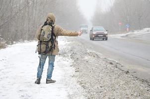 un' uomo con un' grande zaino mostrando pollici su per autostop du foto