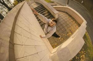 un' giovane tipo supera ostacoli, arrampicata su calcestruzzo muri. il atleta pratiche parkour, formazione nel strada condizioni. il concetto di gli sport sottoculture tra gioventù foto