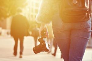 posteriore Visualizza di un' ragazza con un' digitale telecamera su un' affollato strada ba foto