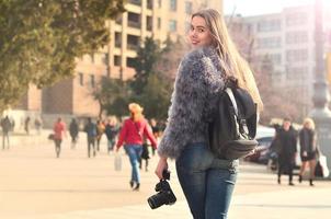 posteriore Visualizza di un' ragazza con un' digitale telecamera su un' affollato strada ba foto