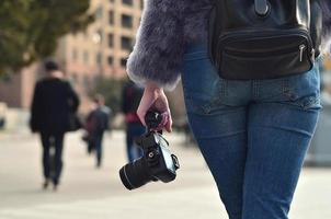 posteriore Visualizza di un' ragazza con un' digitale telecamera su un' affollato strada ba foto