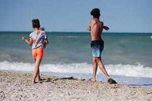 Due fratelli gettare ciottoli in il mare nel spiaggia porto sant elpidio, Italia. foto