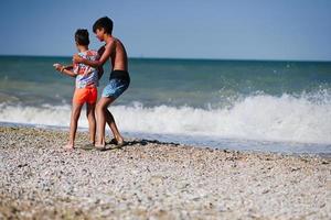 Due fratelli gettare ciottoli in il mare nel spiaggia porto sant elpidio, Italia. foto