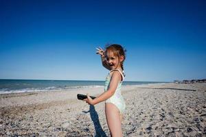 bambino ragazza con Telefono nel mani a mare spiaggia porto sant elpidio, Italia. foto