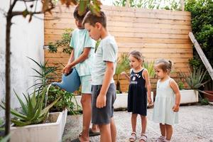 bambini con può irrigazione il fiori su il terrazza di il Casa. foto