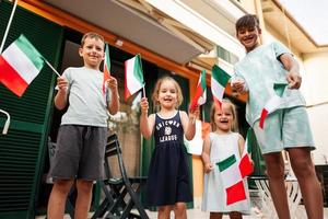 contento quattro bambini con italiano bandiere festeggiare repubblica giorno di Italia. foto