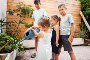 bambini con può irrigazione il fiori su il terrazza di il Casa. foto