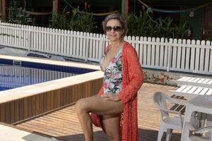 donna indossare un' uno pezzo costume da bagno e colorato copertina su sospeso su di il piscina foto