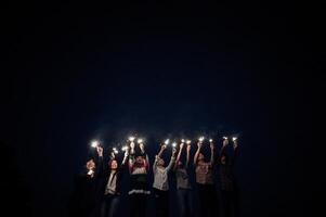 gruppo di giovane amici Tenere e giocare con fuoco ardente sparklers foto