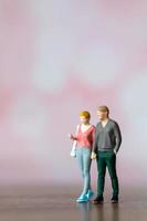 miniatura persone uomo e donna nel casuale stoffa in piedi insieme su rosa sfondo foto