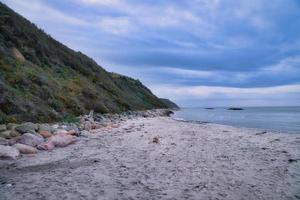 tramonto su il danese costa. spiaggia, onde. collina con alberi nel sfondo. paesaggio foto