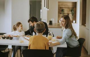 giovane contento famiglia parlando mentre avendo prima colazione a cenare tavolo foto