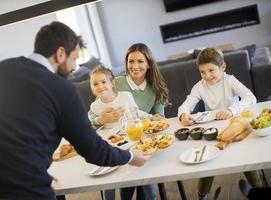 giovane contento famiglia parlando mentre avendo prima colazione a cenare tavolo foto